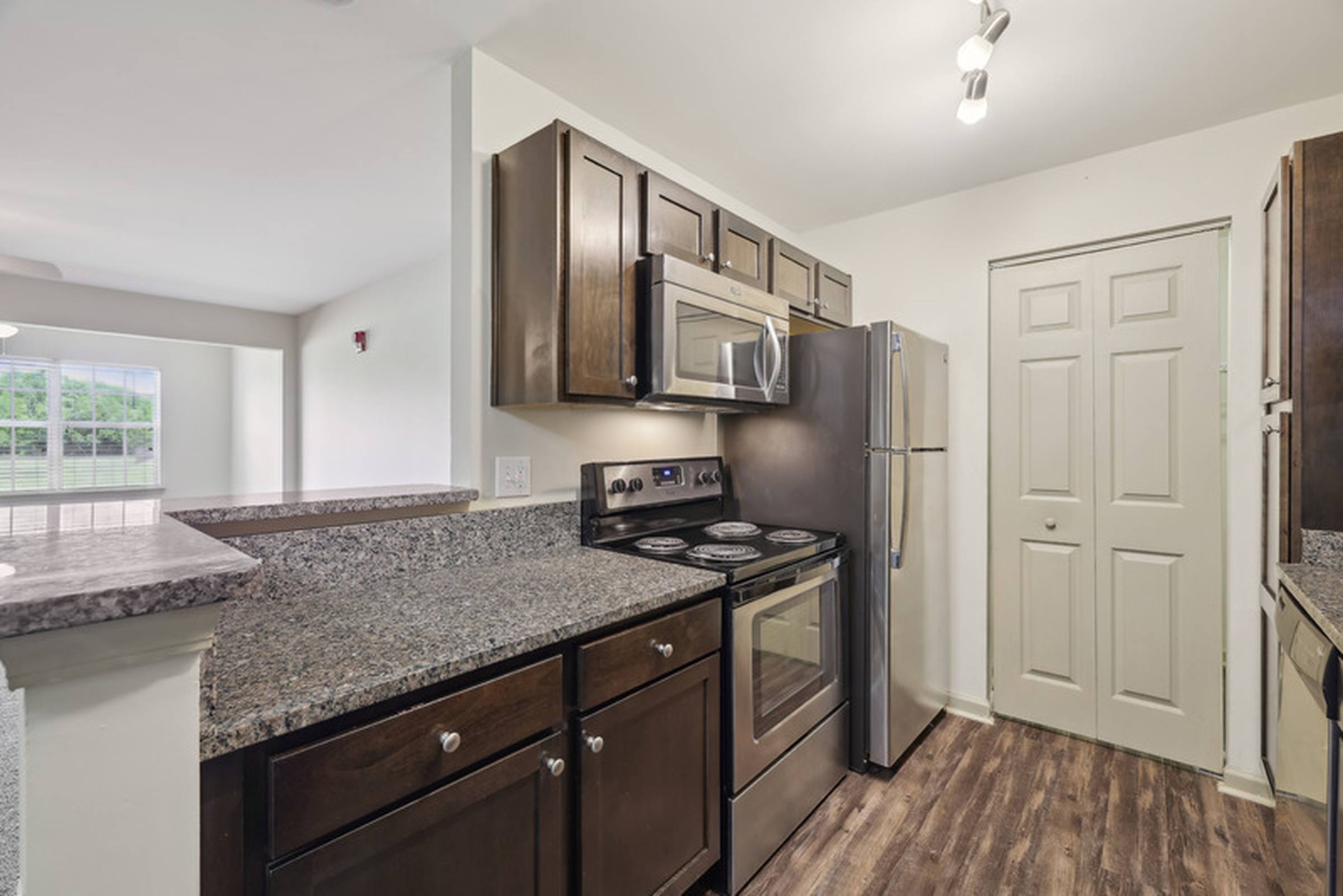 Modern kitchen with dark cabinets, granite countertops, stainless steel appliances, and wood flooring.
